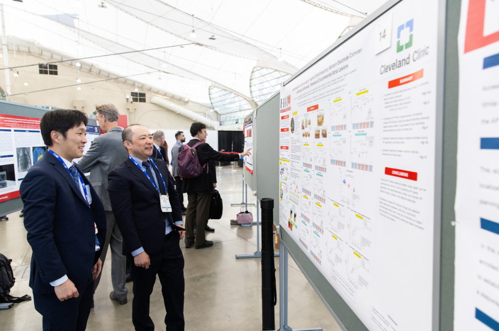 Attendees view and discuss research posters in a bright conference exhibit hall.
