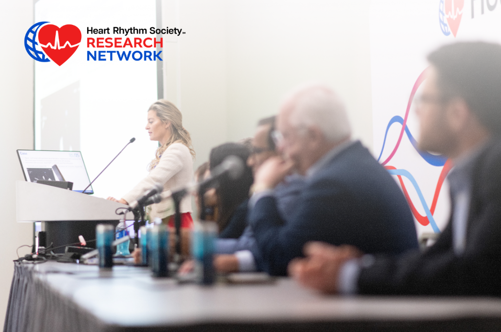 Speaker presents at the podium during a Heart Rhythm 2025 session with panelists seated alongside her.